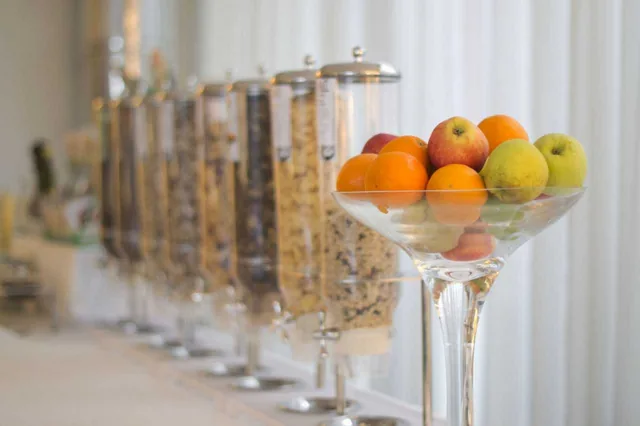Buffet della colazione con dispenser di cereali e coppa di frutta fresca