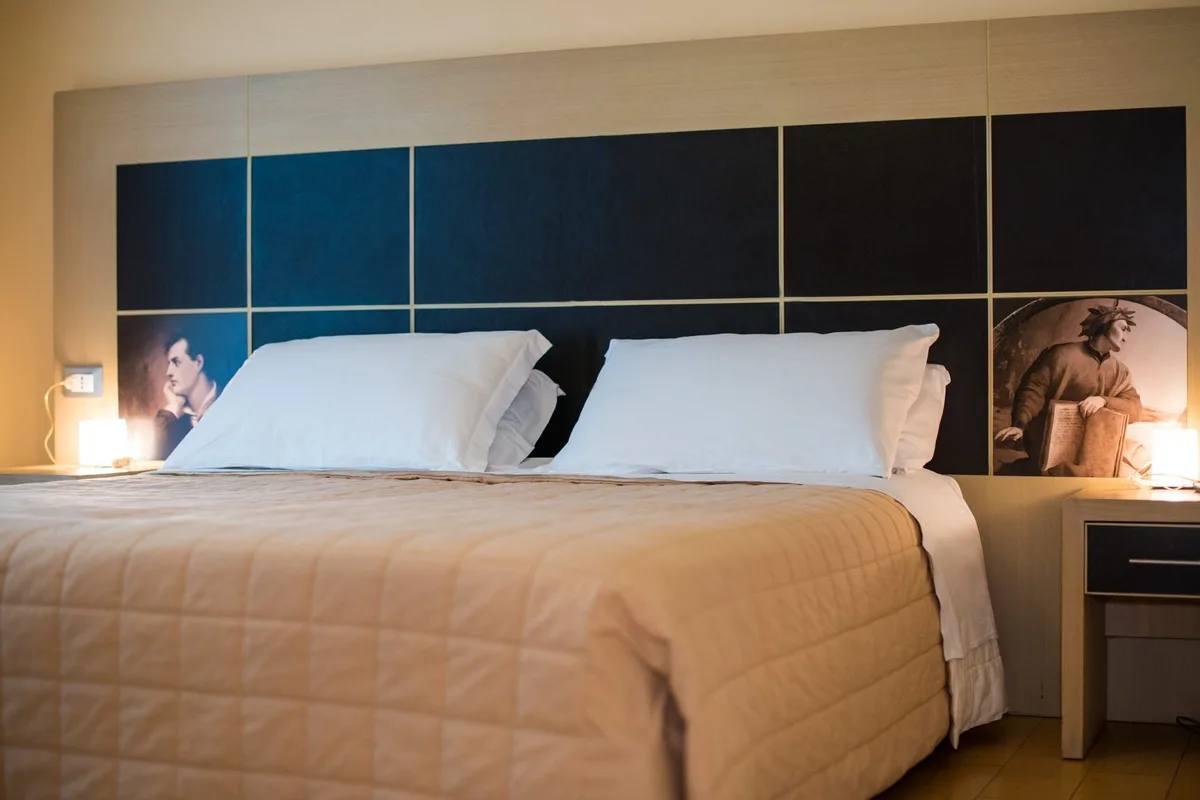Letto matrimoniale con testiera blu e lampada da lettura accesa