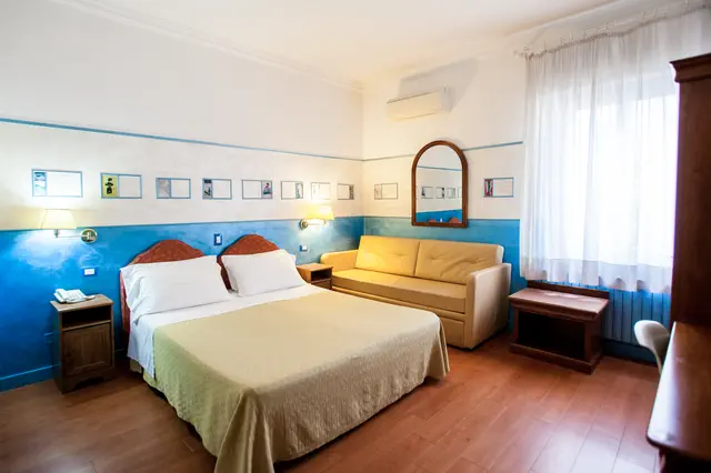 Camera Classic con parete blu, letto e divanetto sotto la finestra